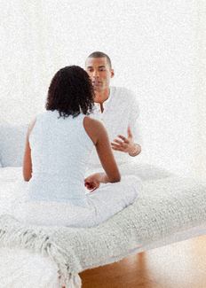 An arguing couple stting on a bed